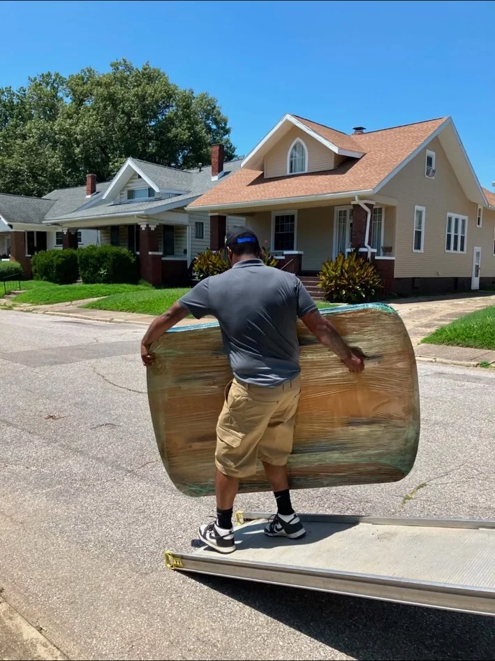 Mover carrying a wrapped item toward a home