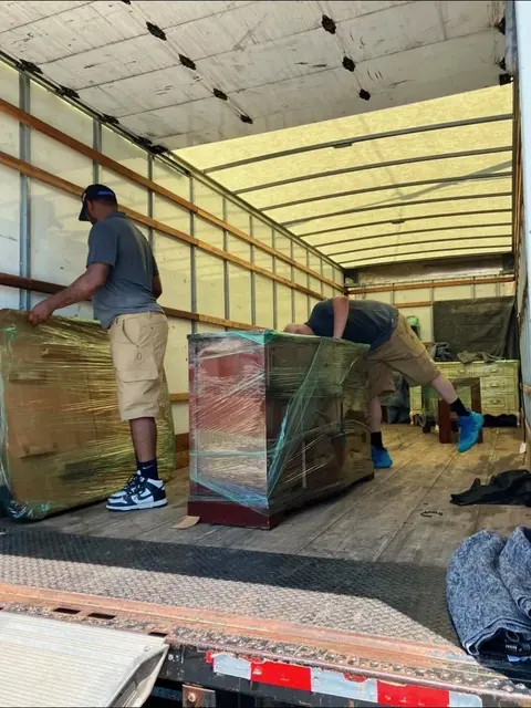 Movers loading wrapped furniture